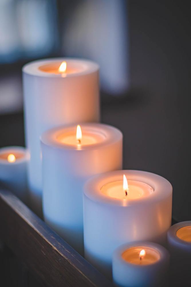 Several white candles burning in dim light