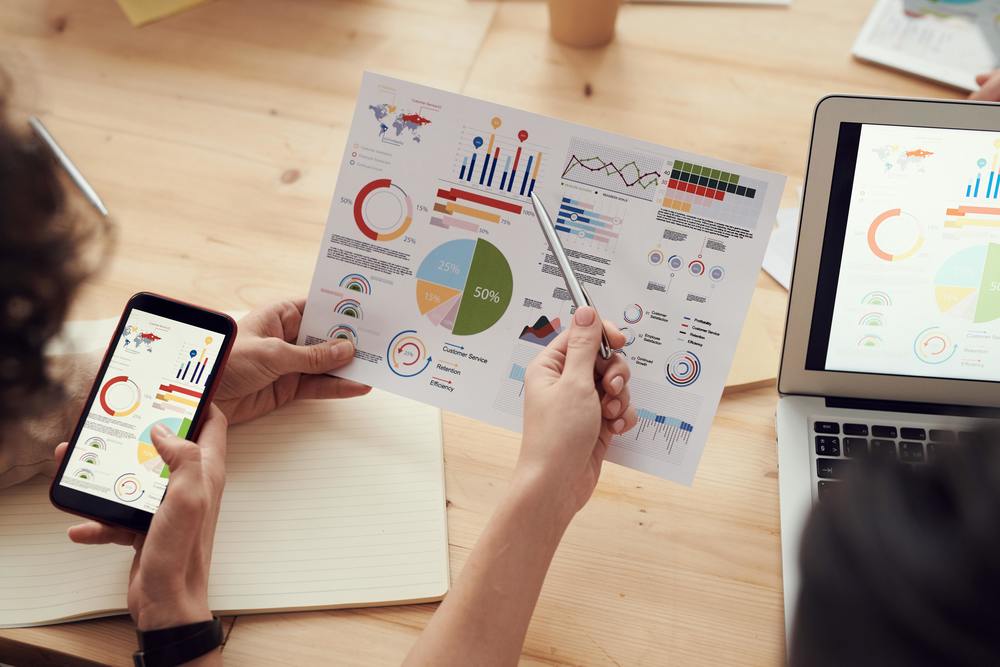 A sheet with different graphs listed on it and the graph list also on a cell phone and laptop