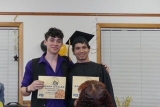 Two graduates holding certificates 