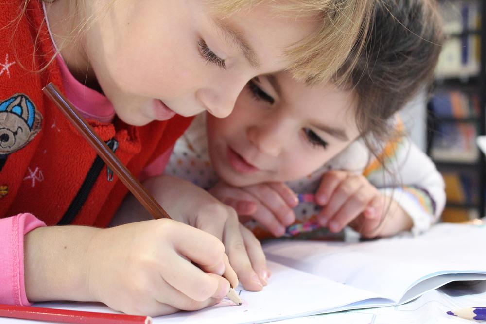 two young girls writing at table