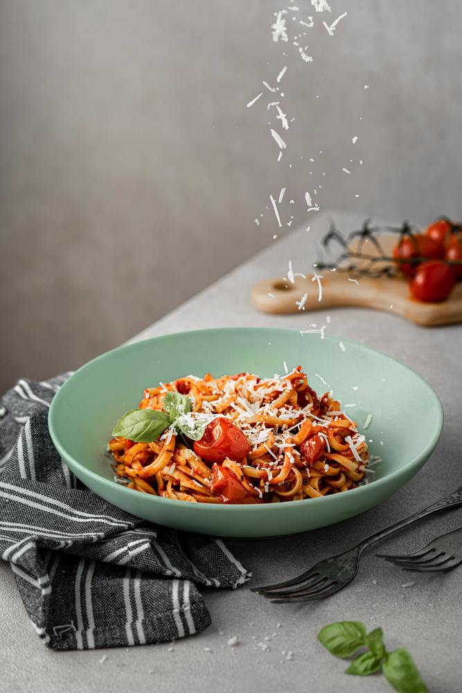 bowl of spaghetti with cheese falling into the bowl