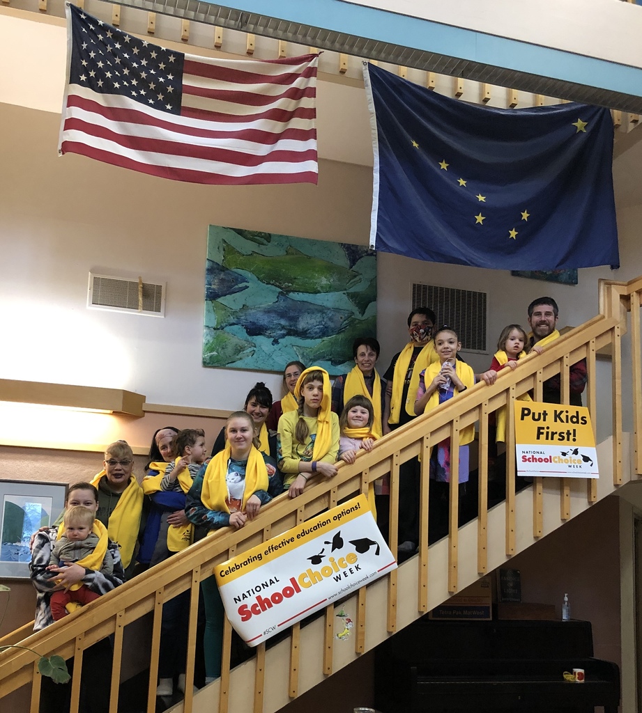 Several students and teachers standing on a stairwell with their yellow school choice scarves on