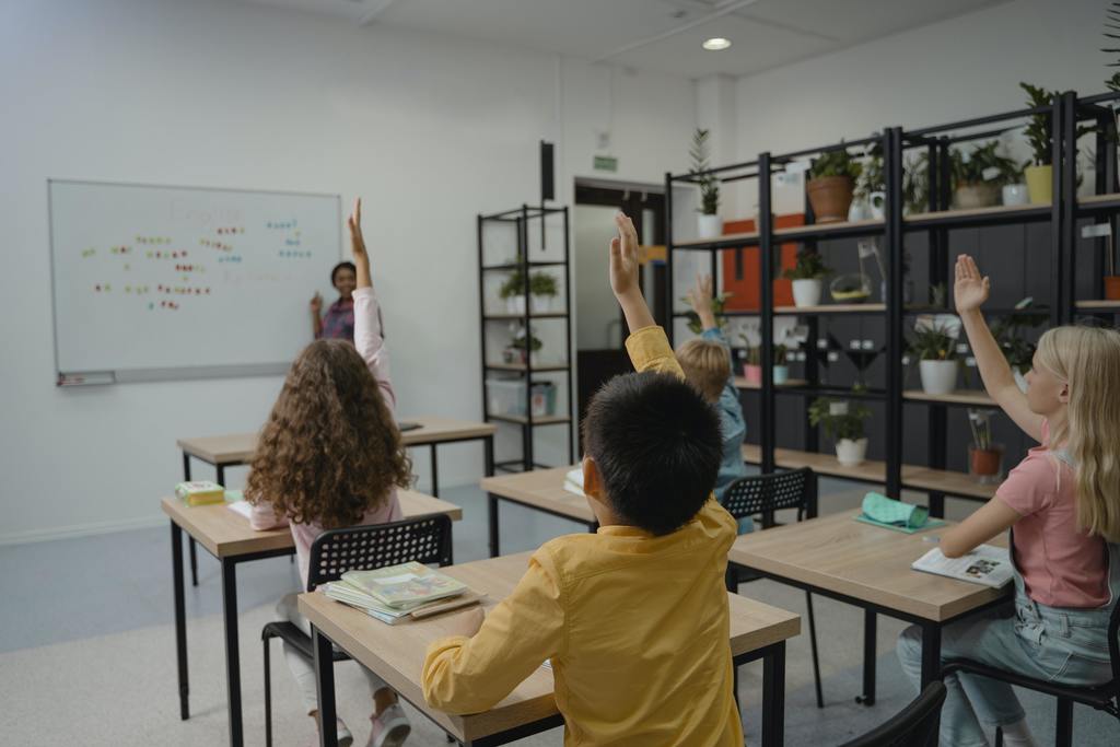 Several students with their hands raised in the classroom setting